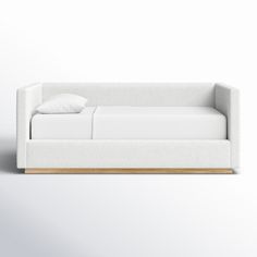 a white couch sitting on top of a wooden floor next to a pillow and blanket