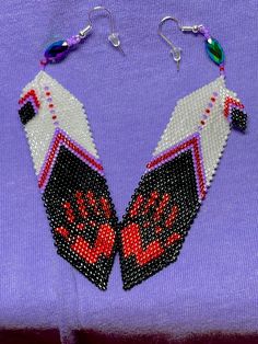 two pairs of beaded earrings on a purple shirt