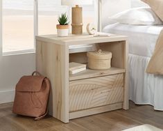 a white bed sitting next to a wooden table with a bag on top of it