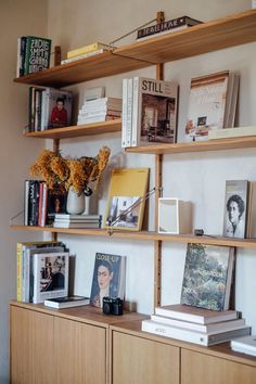 books and magazines are sitting on the shelves in this living room, along with vases filled with flowers