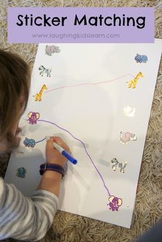 a young child is drawing on a white board with stickers that read sticker matching