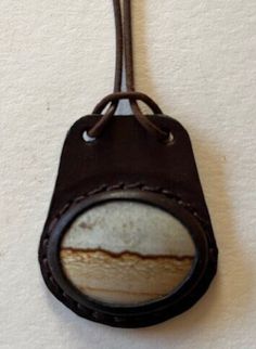 "Leather Necklace with Semi Precious Picture Jasper Cabochon. The leather is cut and wet molded over the cabochon. The two layers of leather are handstitched together and the edges are dyed and waxed.  The rolled leather cord is 20\" long with a stainless steel clasp.  This pendant measures 1 3/4\" wide and 2 1/8\" high. Handmade in California" Necklace With Picture, Picture Jasper, Jasper Stone, Leather Necklace, Leather Cord, Hand Stitching, Semi Precious, Jewelry Necklace Pendant, Two By Two