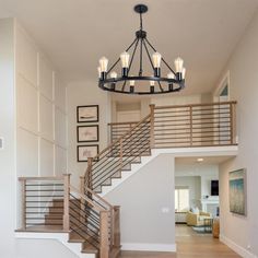 a chandelier hanging from the ceiling in a living room next to a staircase