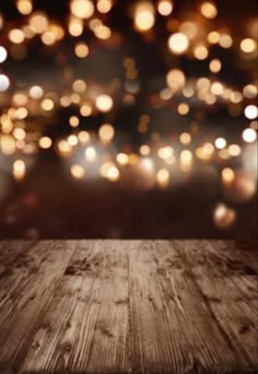 an empty wooden table in front of a blurry background with lights on the wall