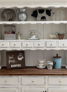 a white hutch filled with lots of different types of dishes and coffee mugs