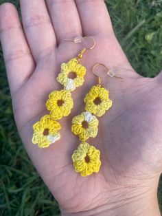 yellow crocheted flower earrings on a person's hand