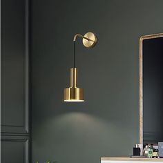 a bathroom with green walls and a gold light fixture hanging from the wall above it