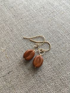 Caramel coffee bean bead gold filled earrings. These gorgeously dainty earrings are the perfect pick me up for the coffee lover. They are a delicious gingerbread caramel option newly added to the range of coffee bean earrings available from my Etsy shop. Each coffee bean bead is 11mm x 8mm in size.   The appointment length of the earrings is 16mm, not including ear fittings. You can choose the type of ear fitting you would like from the drop down menu. So what is gold filled? The answer is that Handmade Dainty Brown Jewelry, Everyday Hypoallergenic Brown Earrings, Everyday Hypoallergenic Brown Jewelry, Gingerbread Caramel, Gingerbread Coffee, Bean Earrings, Coffee Bean Earrings, Caramel Coffee, Gold Filled Earrings