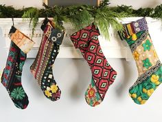 christmas stockings hanging from a mantel with greenery