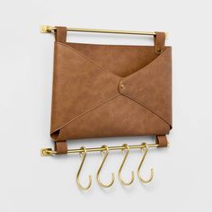 an envelope hanging on a wall with three hooks attached to it and two gold handles