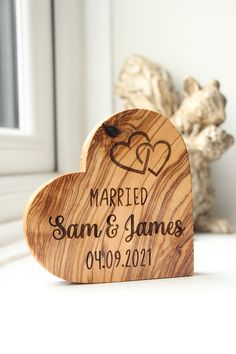 a wooden heart shaped sign sitting on top of a white table next to a window