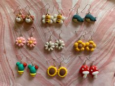 the earrings are all made up of different colors and shapes, including mushrooms, flowers, and bees