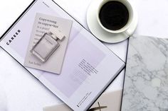 a cup of coffee next to an open book on top of a marble countertop