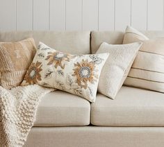 a couch with several pillows on top of it next to a blanket and pillow case