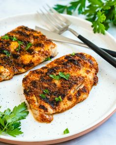 two pieces of chicken on a plate with parsley