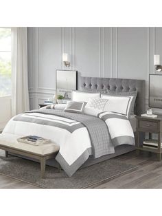 a bed with white and grey sheets in a room