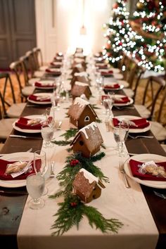 a long table is decorated with gingerbread houses and greenery as well as place settings