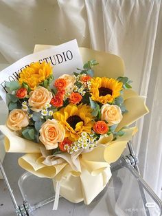 a bouquet of sunflowers and roses is sitting on a chair next to a sign