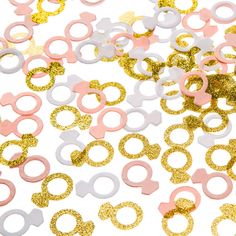 pink, white and gold confetti with bows on them are scattered over a white background