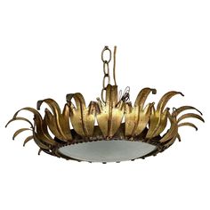 a chandelier hanging from the ceiling with gold colored metal petals and leaves on it