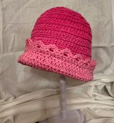 a pink crocheted hat sitting on top of a mannequin head