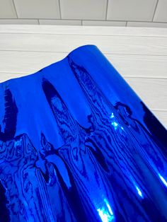 a blue vase sitting on top of a wooden table next to a white tile wall