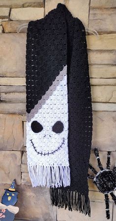 a black and white crocheted scarf hanging on a wall next to a spider