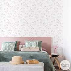 there is a bed with pillows and blankets on the headboard, in front of a wallpapered background