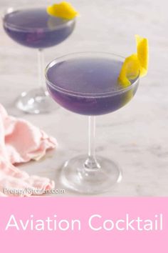 two glasses filled with purple and yellow cocktails on top of a white countertop