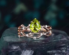 a yellow diamond ring on top of a rock with diamonds around it and an oval green stone