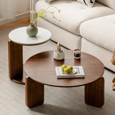 two coffee tables sitting on top of a carpeted floor next to a white couch