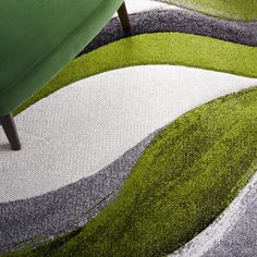 a green chair sitting on top of a rug next to a white and gray couch