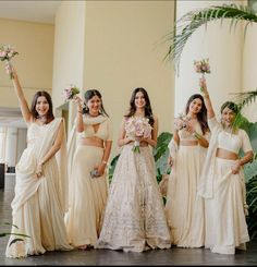 the bridesmaids are all dressed in white and holding bouquets with their hands up