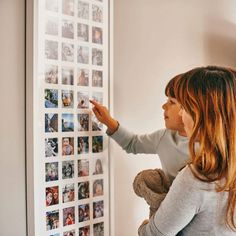 a woman is pointing at pictures on the wall with a teddy bear in front of her