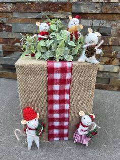 two little mice are sitting in front of a box with plants and decorations on it