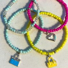 Set Of 4 Stretch Bracelet In Spring Pastels: Yellow, Pink , Baby Blue. Enameled Purse Charms On Two Of The Bracelets And An Open Silver Tone Heart On Another. A Fun, Flirty Spring Set . Handcrafted By Shar Handmade Trendy Yellow Bracelets, Trendy Handmade Yellow Bracelets, Adjustable Neon Yellow Summer Jewelry, Yellow Beaded Bracelets For Summer, Yellow Beaded Bracelets For Everyday Summer Wear, Trendy Yellow Bracelets With Round Beads, Trendy Yellow Round Beads Bracelet, Trendy Yellow Beaded Bracelet, Cute Yellow Bracelet For Everyday Wear