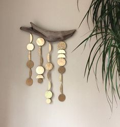 a wall hanging made out of coins and wooden spoons next to a potted plant