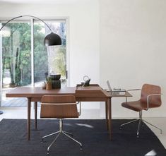 an office with a desk, chair and lamp in it's center area next to a large window