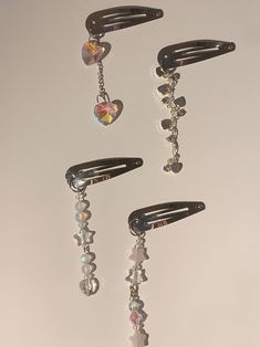 three pairs of hair clips with dangling beads and heart shaped charms hanging from the ends