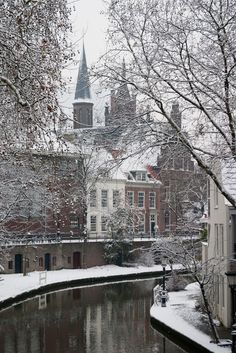 a river running through a snow covered city next to tall buildings with spires on top