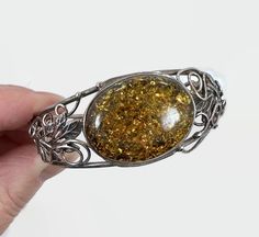 "Stunner! This is a vintage sterling silver bracelet set with a large piece of polished Tony amber. The amber is accented with leaves and flowing sterling accents that curl here and there. This is a hinged cuff or bangle bracelet. It closed with a side slide claps and has a safety chain. So pretty and is inspired by the Art Nouveau style. Condition: Very good vintage condition, vintage patina Measurements: 6 3/4\" inside Width: 0.96\" or 24.45 mm wide Weight: 26.2 grams Markings: Unmarked, teste Vintage Handmade Sterling Silver Bracelet In Antique Silver, Victorian Bracelets With Polished Finish As Gift, Victorian Bracelets With Polished Finish, Silver Cabochon Cuff Bracelet Gift, Victorian Bracelet With Polished Finish As Gift, Handmade Vintage Sterling Silver Bracelets, Antique Handmade Adjustable Sterling Silver Bracelet, Unique Antique Silver Bracelet For Gift, Silver Sterling Silver Cuff Bracelet With Cabochon