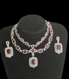 Enhance your elegance and add a touch of sparkle to your ensemble with this stunning Silver Finish, and ruby red (hot pink)American Diamond double layer Neck Line accompanied by matching Dangle Earrings. The necklace features a captivating silver finish that exudes sophistication, while the vibrant red American diamonds and shimmering diamonds create a mesmerizing focal point. Each carefully crafted stone is expertly placed to maximize brilliance and create a dazzling effect. The necklace line s Elegant Red Festive Jewelry, Ruby Jewel Bridal Necklace Gift, Elegant Ruby Bridal Necklace For Festive Occasion, Elegant Ruby Bridal Necklace For Festive Season, Ruby Necklace For Party, Fine Jewelry, Elegant Ruby Jewelry Sets For Celebration, Exquisite Gemstone Bridal Necklace For Party, Formal Ruby Jewelry Sets For Festivities, Luxury Red Jewelry Sets For Wedding