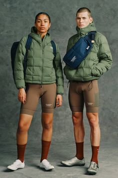 two men standing next to each other in shorts and jackets with backpacks on their backs