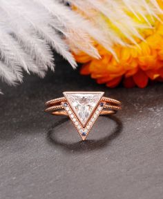 a white diamond ring sitting on top of a table next to some flowers and feathers