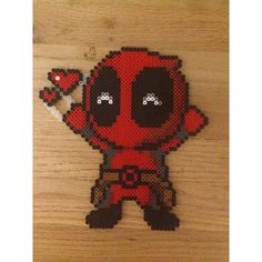 a cross stitch deadpool character on a wooden surface