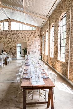 a long table with white chairs is set up in the middle of an empty room