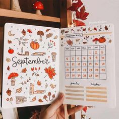 someone is holding up a planner with autumn decorations on it and the calendar in front of them