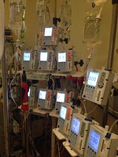 several medical devices are arranged in a room with multiple monitors on the wall and hanging from the ceiling