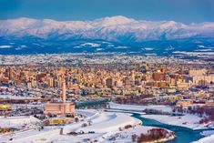 an aerial view of a city with mountains in the background and snow on the ground