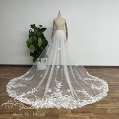 a white wedding dress on display in front of a potted plant and wooden floor